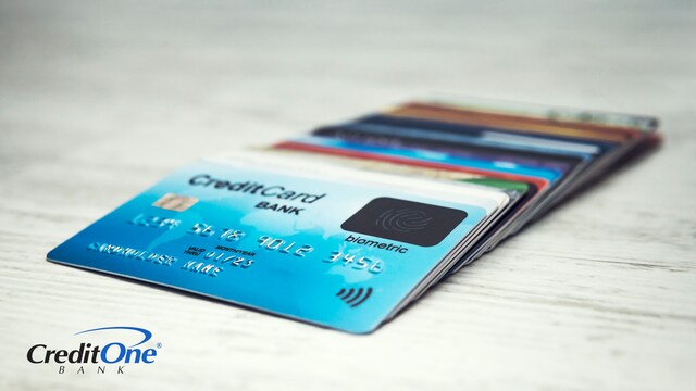 A fanned-out pile of payment cards sits on a table with a credit card on top of the rest, representing the benefits of using credit cards over other cards.