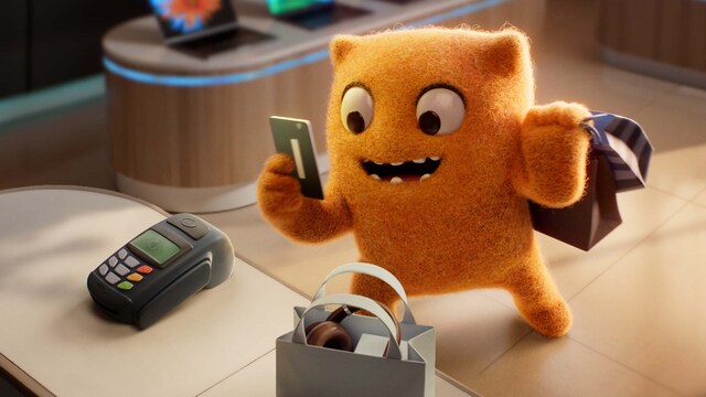 Max Out at the register holding a credit card to complete his shopping purchase